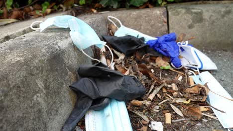 dirty disgusting disposable corona virus face masks and latex gloves among cigarette rubbish on street curb rising left dolly