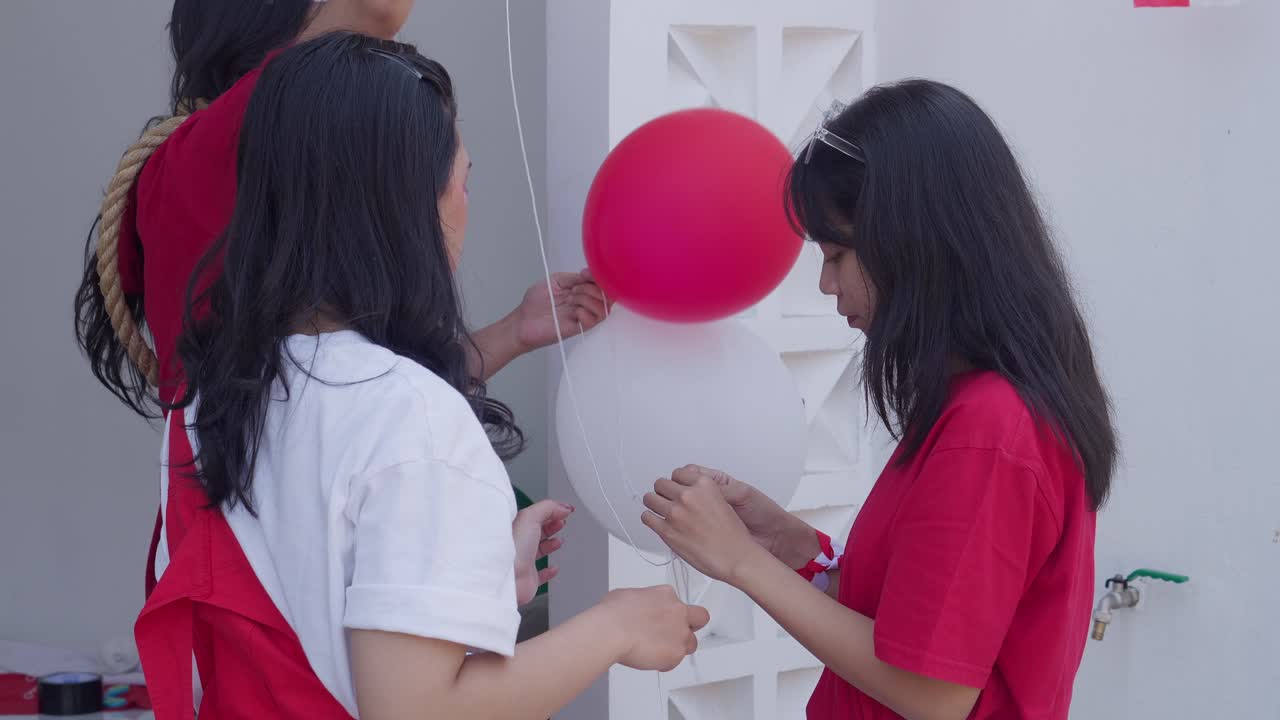 Young Man And Woman Working Together To Arrange Decoration For Indonesia Independence Day.