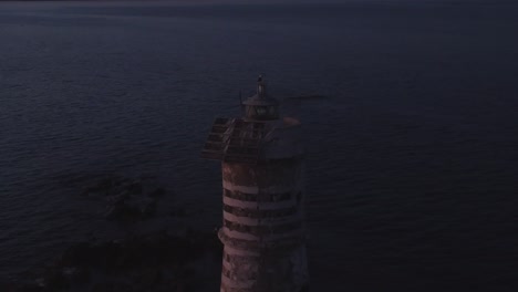 static cinematic establisher shot of flashing offshore lighthouse at dusk