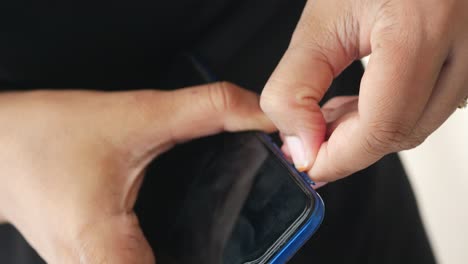 woman repairing a broken phone screen with a pick