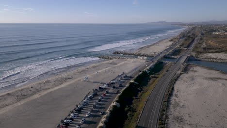 aerial view of coastal beach with ocean waves, river mouth, and parallel road