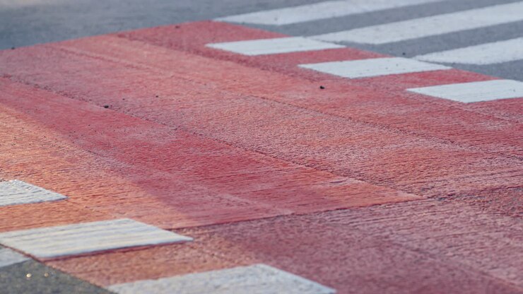 Closeup car driving crosswalk in town. Marked red white pedestrian crossing.