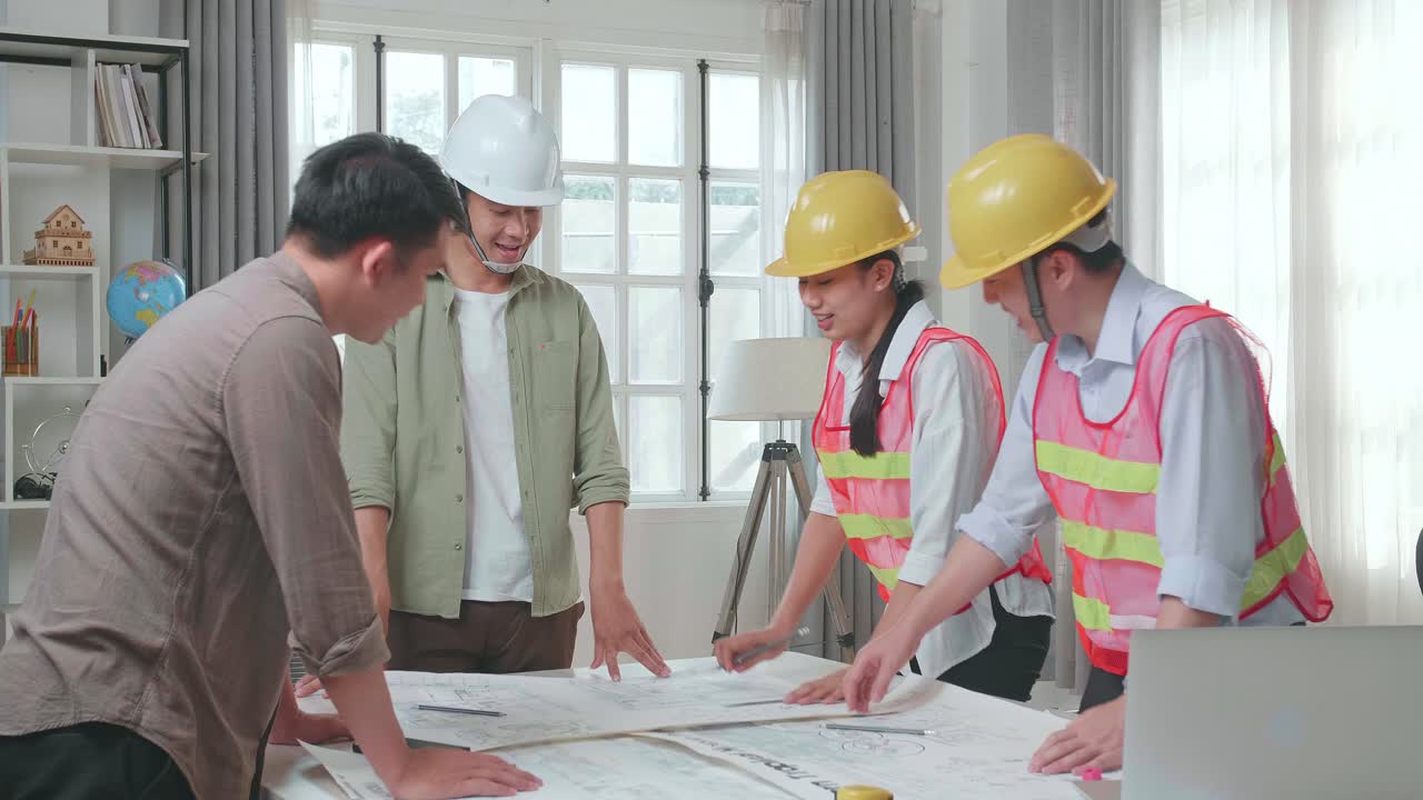 Three Asian Engineers With Helmets And A Man Celebrating Finish Drawing Building Construction While Working At The Office
