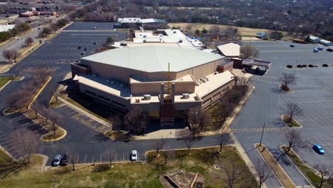 An aerial shot of a mega church with a huge cross in front of it.