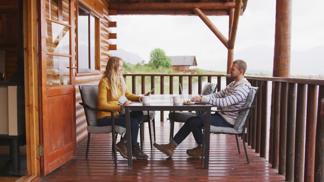 pareja caucásica pasando tiempo en casa juntos, sentados fuera de la cabaña