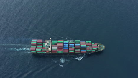 logistics cargo ship transports freight containers - motoring in ocean as seen from drone