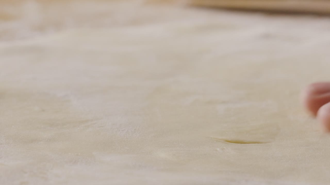 Hands Rolling Out Dough on Floured Table