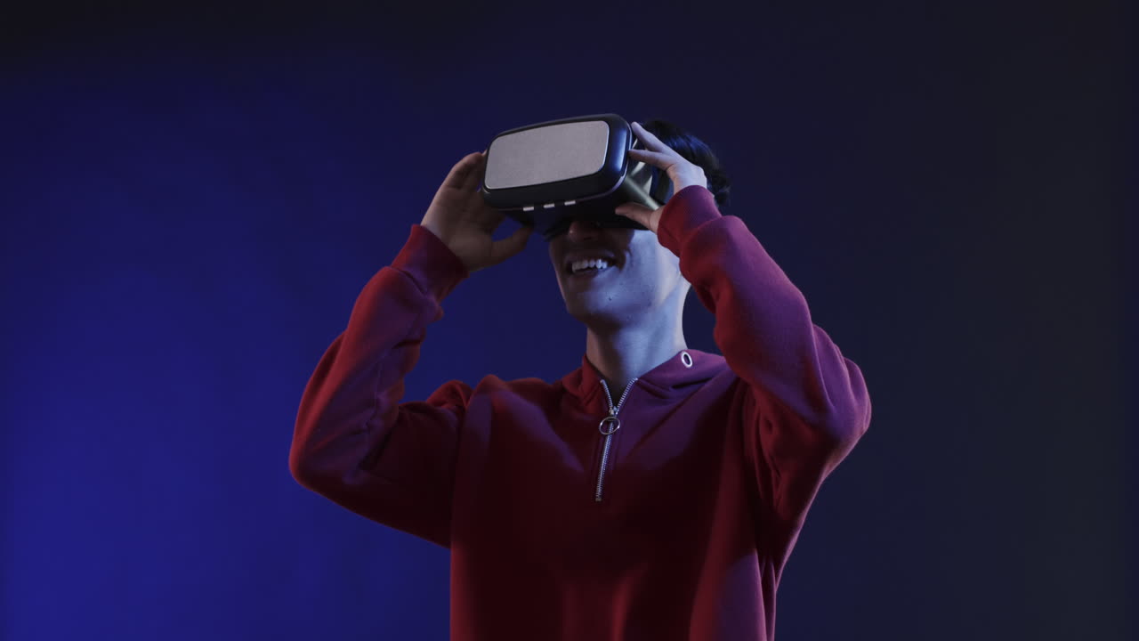 Asian man using vr headset on blue background, slow motion