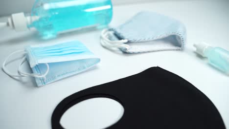 slow movement close up shot of three different face masks and blue hand gel sanitize on white table to protect corona-virus or covid-19