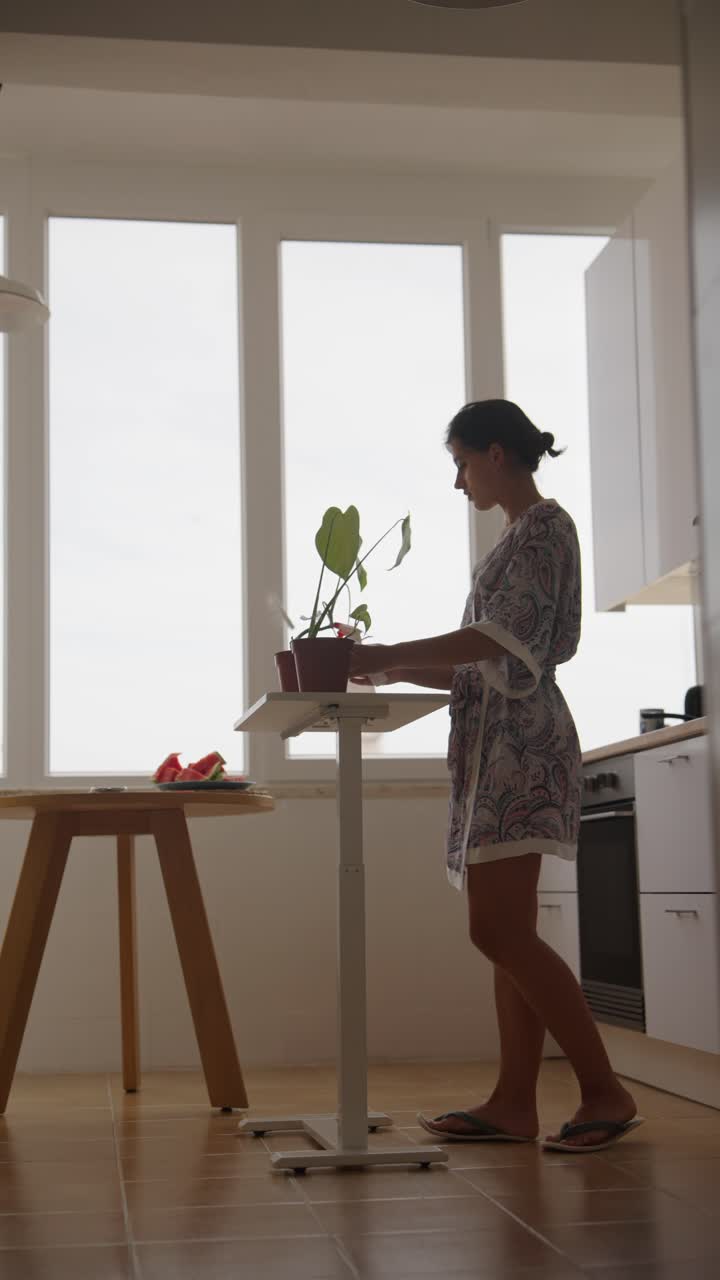 Woman Caring for Houseplants in a Kitchen