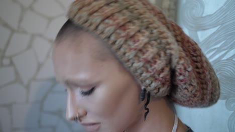 portrait shot of a young woman with alternative clothing and tattoos is leaning towards a mosaic wall looking hopeless, nervous and stressed