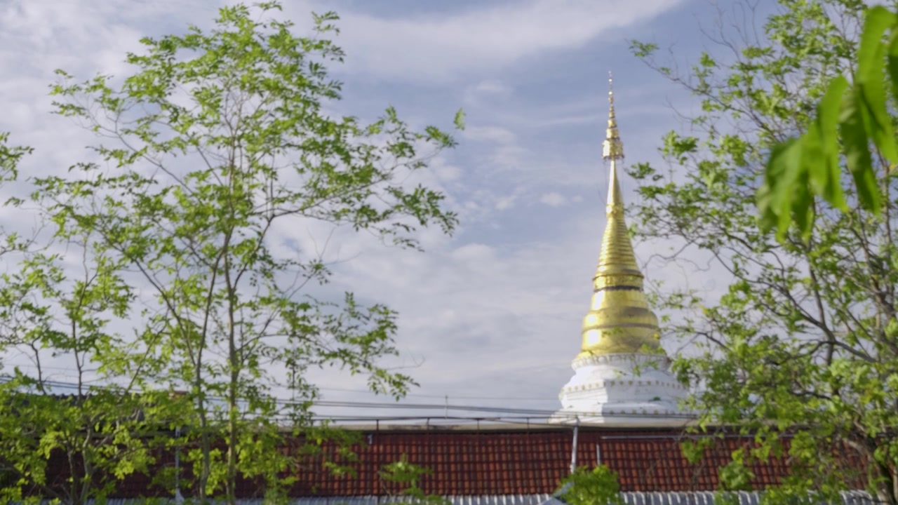 Veduta al rallentatore di una Stupa dorata che spunta tra gli edifici in Thailandia.