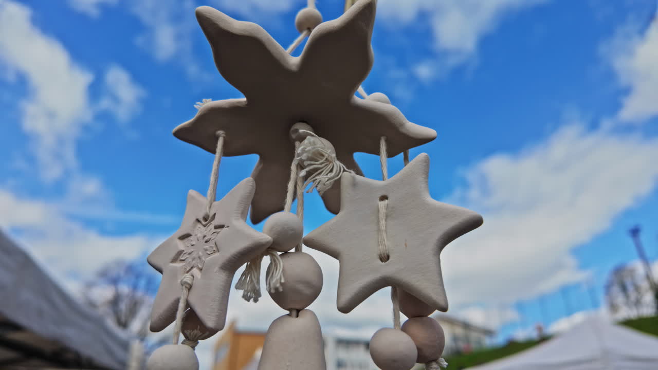 Star-shaped Wind Chimes Hanging Outdoors Against Sunny Blue Sky With Clouds