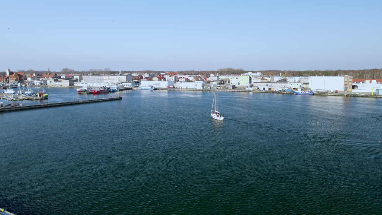 velero blanco entra en el puerto en las tranquilas aguas de city hel en puck bay, cámara lenta aérea