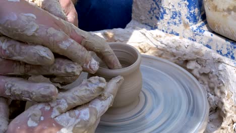 man and woman potter's hands work with clay on a potter's wheel