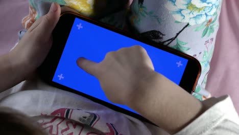 un teléfono inteligente en manos de un niño, la pantalla está retroiluminada con una indicación de color azul.