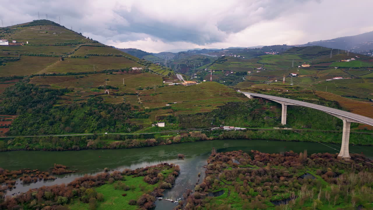 Drone che attraversa una strada sopra un fiume in un paesaggio verde. Ponte alto