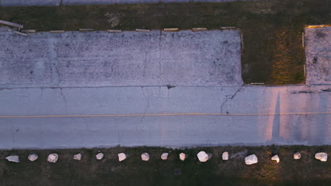 drone top down pan across empty old parking lot with long shadows from barrier rocks