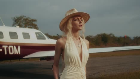 woman in stylish dress at the airport, next to a private jet