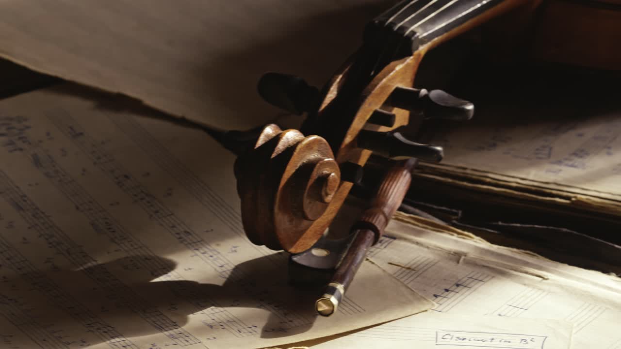 Aged Violin neck scroll revealed laying on sheet music in moody light