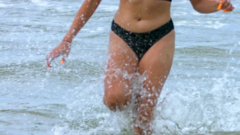 close up of legs and belly of a woman in a bikini running out of the water