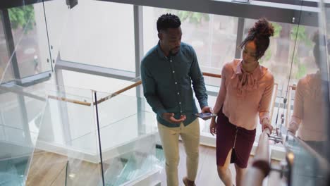 Diverse-business-people-discussing-with-tablet-and-walking-in-creative-office