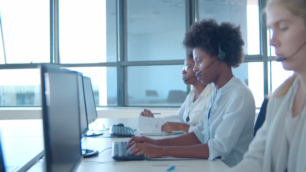 Focused diverse consultants in headsets working at computers