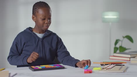 boy on asd spectrum at home solving shape puzzle sitting at table