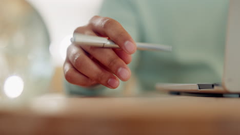 Laptop,-hand-and-holding-a-pen-on-a-table