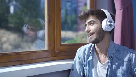 man looking out the window and listening to music with headphones.