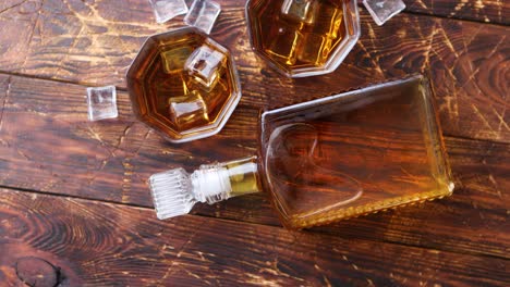 bottle of whiskey with two glasses placed on rustic wooden table