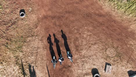 aerial view of three men starting motocross race on a dirt road in the forest