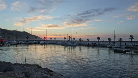 time-lapse video of numerous boats parked in a busy port during magical golden hour, as sky is bathed in warm hues and water shimmers in sunlight