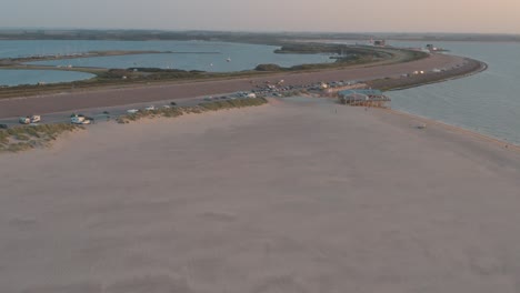 drone cinematográfico - toma panorámica aérea de la playa natural verde y arenosa al atardecer con turistas en zelanda en el mar del norte, países bajos, 25p