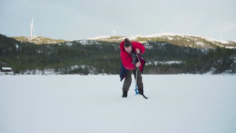 Mann-Bohrt-Ein-Loch-Auf-Einem-Zugefrorenen-See-Zum-Eisfischen