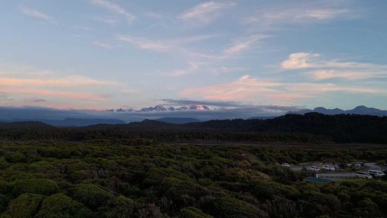 Stunning Sunset View of Snow-Capped Mountains and Lush Forest