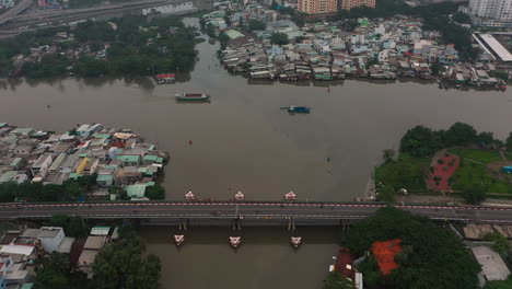 Foggy,smoggy-early-morning-drone-footage-flying-in-towards-the-junction-of-major-canals-with-working-boats,-road-systems,-bridges-in-Saigon,-Ho-Chi-Minh-City,-Vietnam