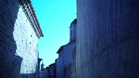 small alley in boulbon in france with stone houses and a church tower belfry above the town