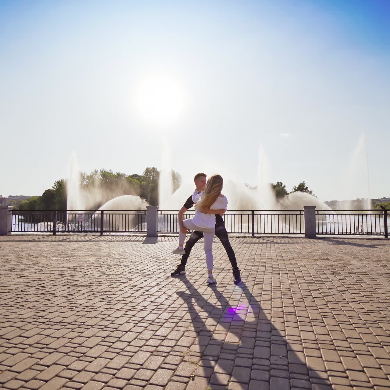 Modern dancers are dancing in the street. Urban lifestyle. Hip-hop generation. Boy's and girl's emotional moves on the video. Paving stones and young dacing couple at fontain background.
