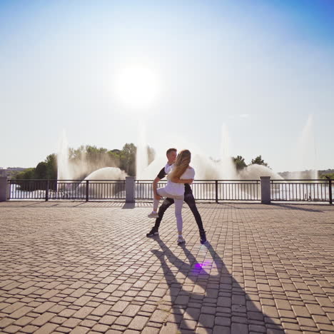 modern dancers are dancing in the street. urban lifestyle. hip-hop generation. boy's and girl's emotional moves on the video. paving stones and young dacing couple at fontain background.