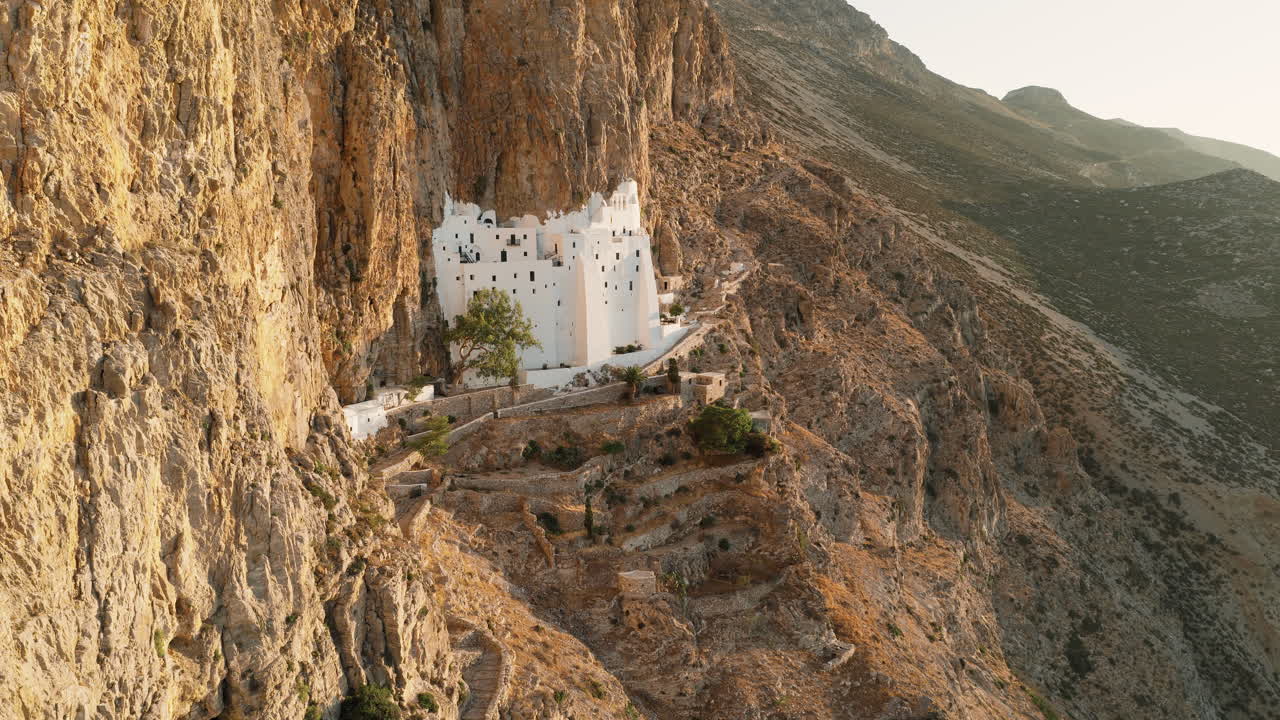 Holy Monastery of the Virgin Mary Chozoviotissa, The Panagia Hozoviotissa Monastery on steep cliffside at sunrise, Amorgos Island, Aerial tracking shot