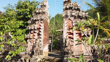 temple gate entrance architecture in beautiful green village with blue sky bali indonesia plants and palm trees waving, religious and calm atmosphere sidemen karangasem