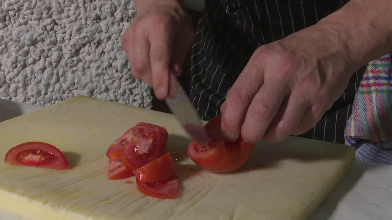 셰프가 토마토를 잘라내고 있습니다.