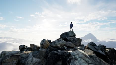 Adventurous-Male-Hiker-Standing-on-Rocky-Cliff-surrounded-by-Mountains