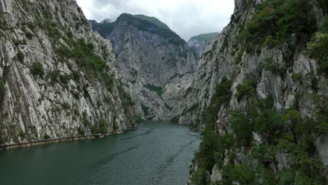 the serene komani lake surrounded by steep, rocky mountains, aerial view