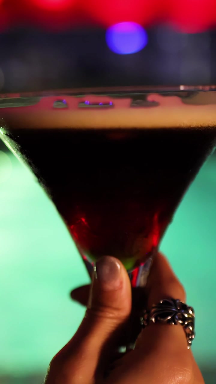 Mano che tiene un cocktail Espresso Martini in discoteca