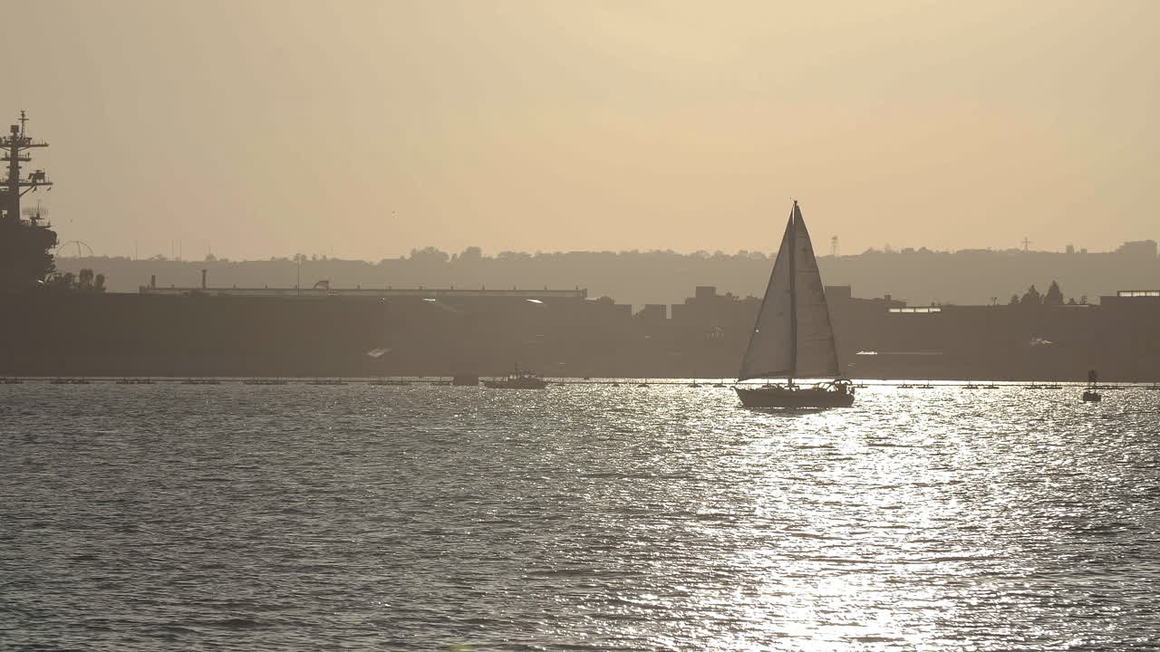 Sailboat and Aircraft Carrier at Sunset