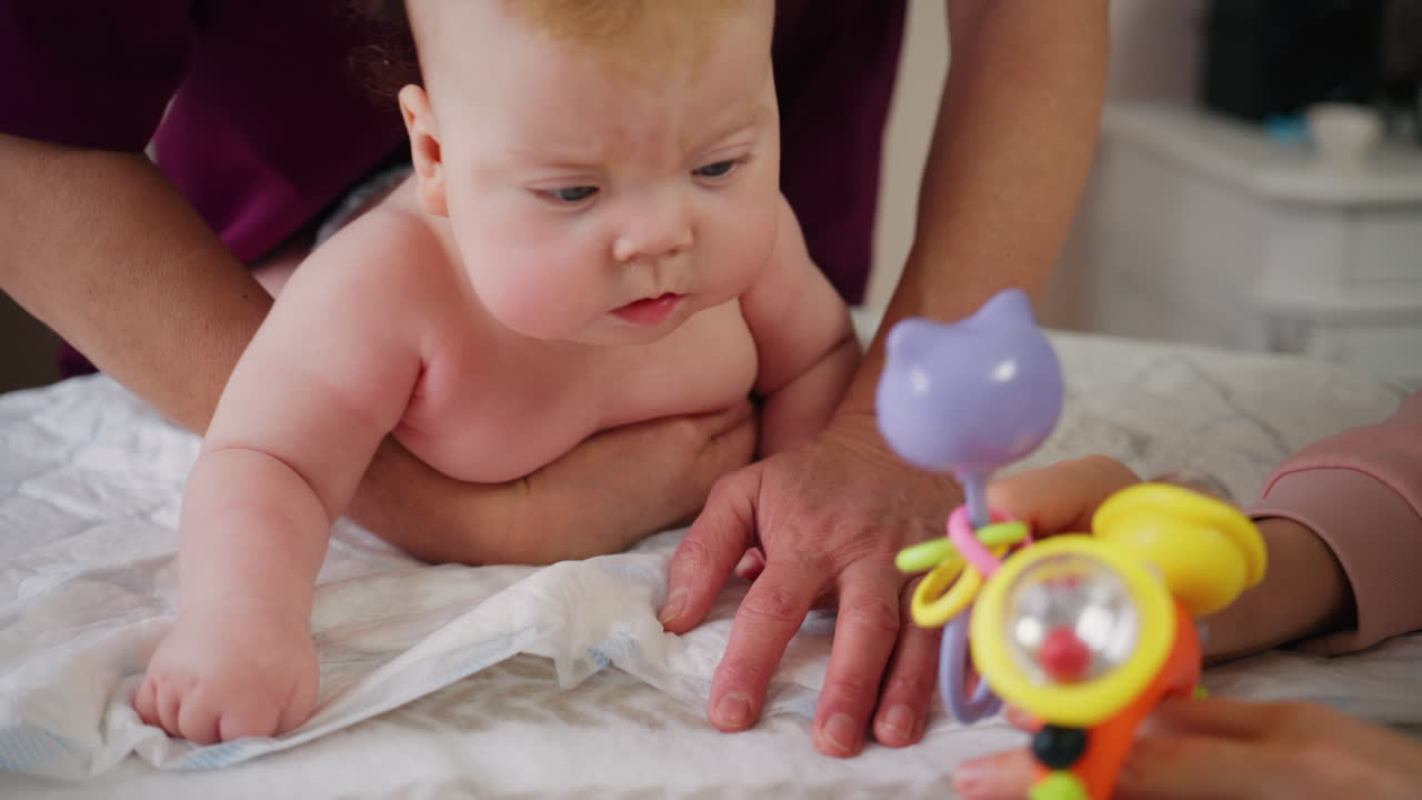 Infant focusing on a bright toy while supported during tummy time
