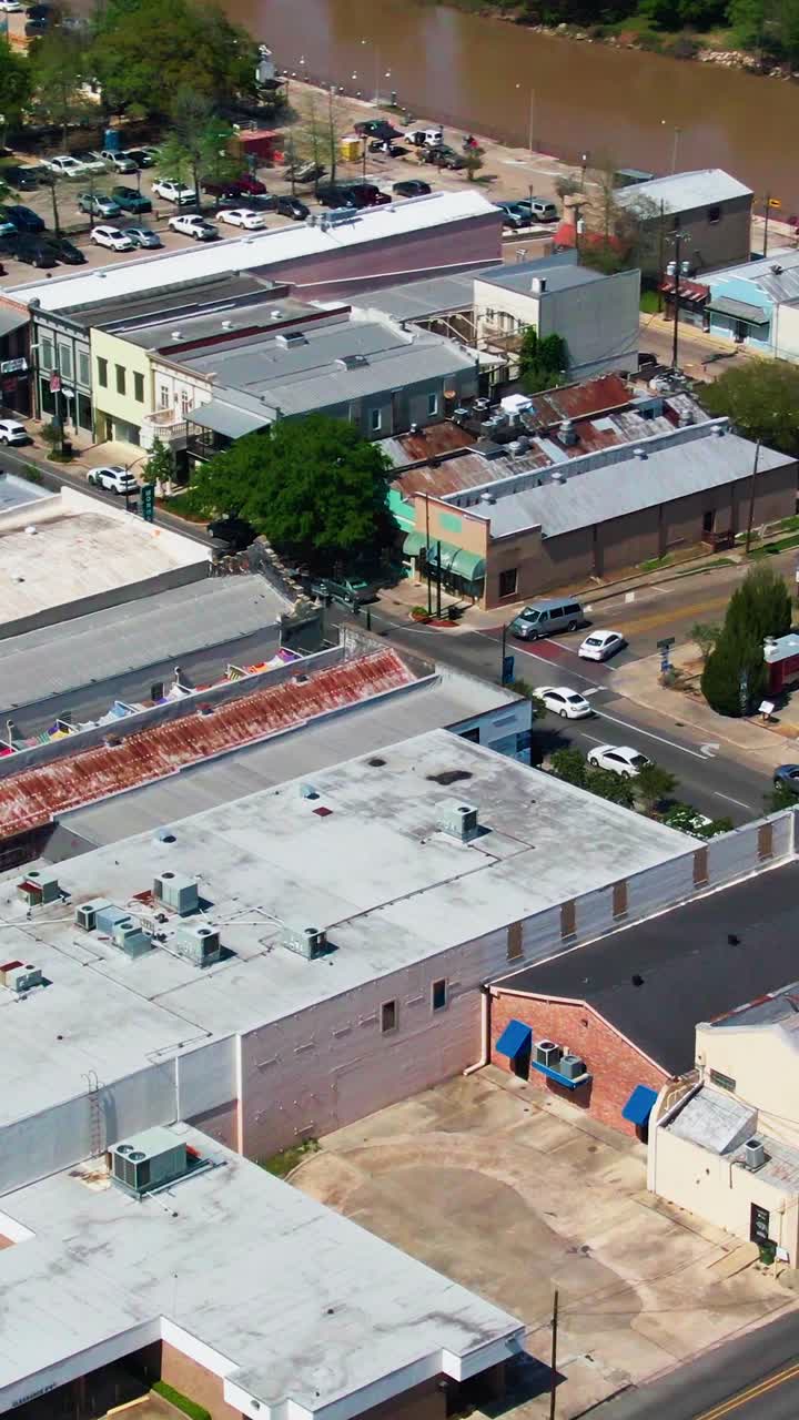 Vertical drone shot over the intersection of Bridge Street and Main Street in New Iberia, LA, showing vehicles, storefronts, and parking areas in the downtown district
