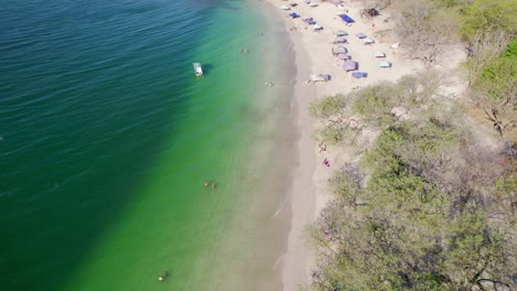4k sobrevuelo aéreo de drones destino turístico popular playa tropical de conchal costa rica con personas y tiendas de playa en la orilla